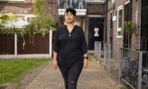 Dot Dot Dot guardian walking in front of block of flats.
